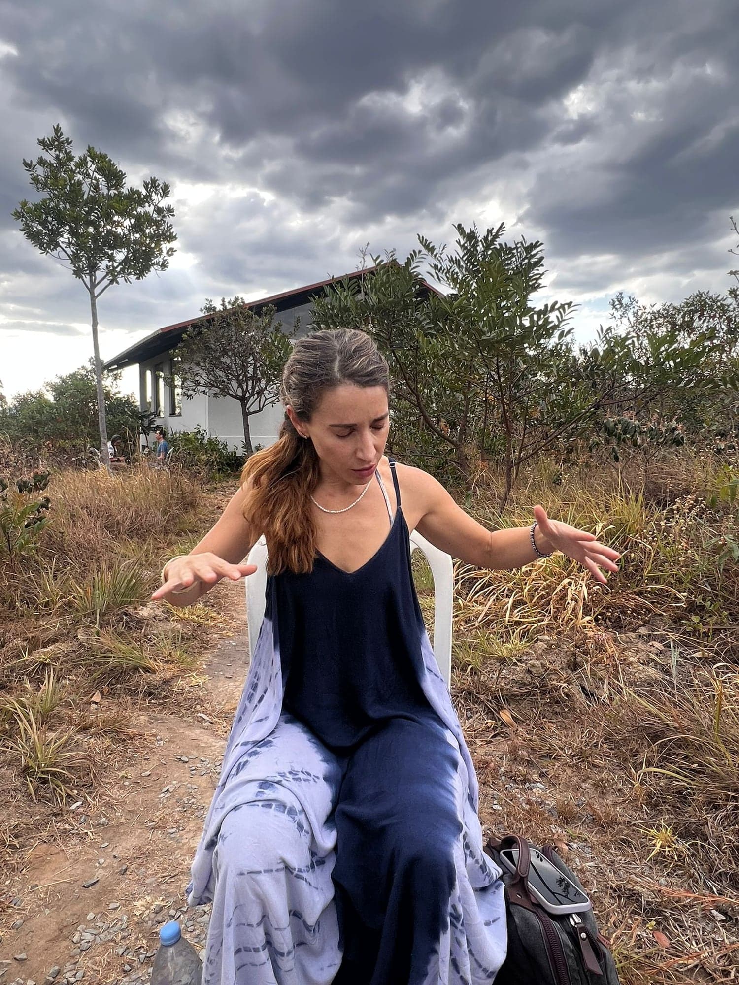 Reading the field outdoors under a storm sky, hands open, eyes closed.