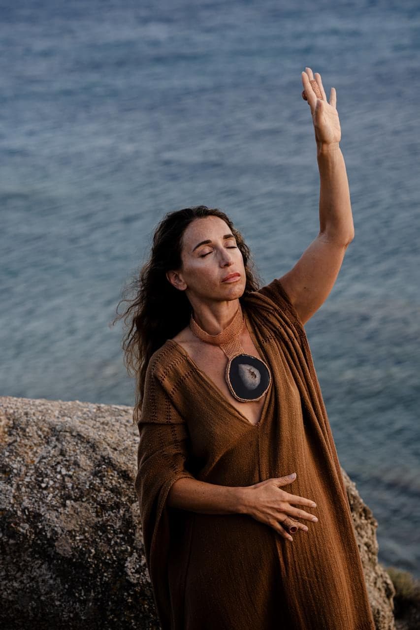 In an ochre wrap by the sea, one hand raised, the other on my belly.